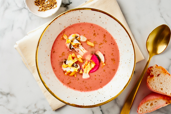 Une soupe froide rose garnie de légumes et d’herbes fraîches.