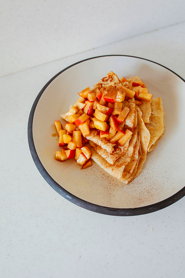 Crêpes fines servies avec des morceaux de fruits frais.