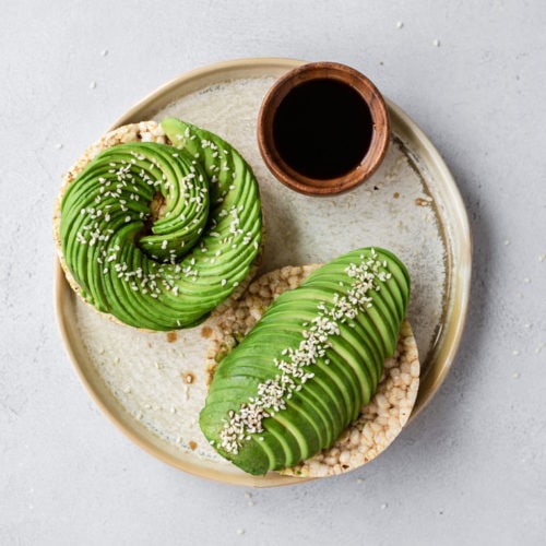 Toast à l'avocat en forme de rose avec graines de sésame et une fleur comestible.