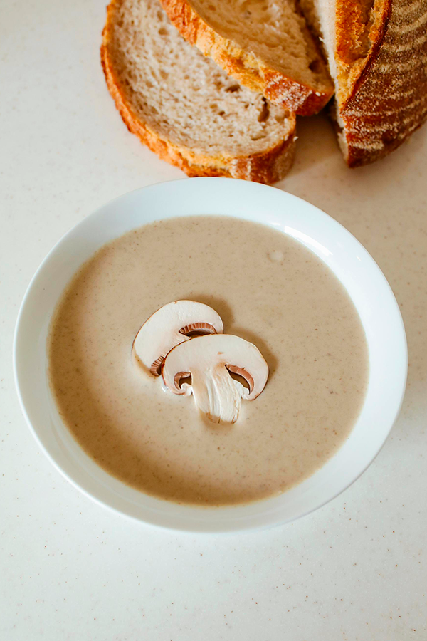 soupe aux champignons avec quelques tranches de champignons en garniture, accompagné de pain.