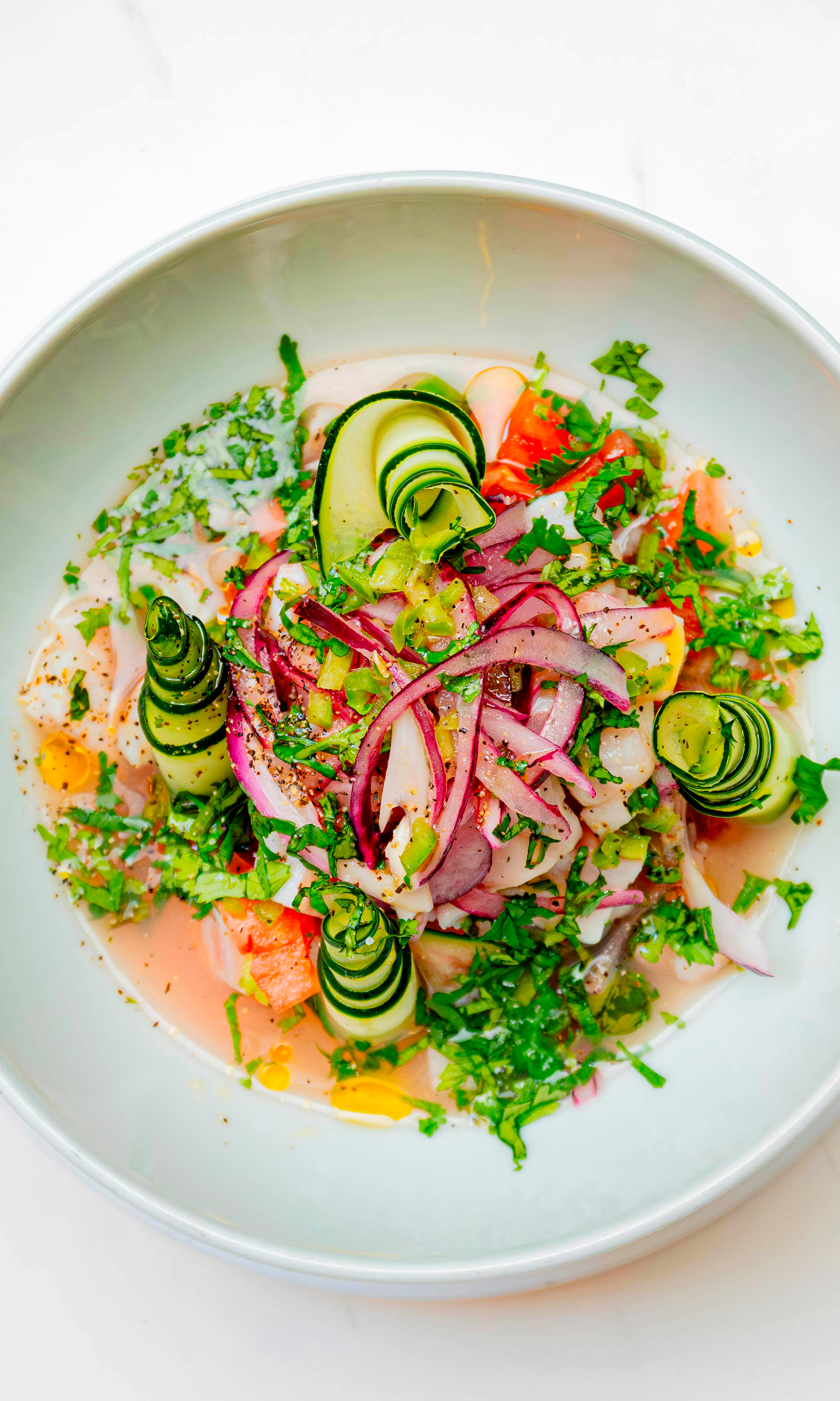 Salade fraîche et colorée avec légumes en spirales, herbes fraîches et divers ingrédients.
